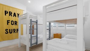Una habitación con literas, un cartel amarillo con texto y un armario de madera.