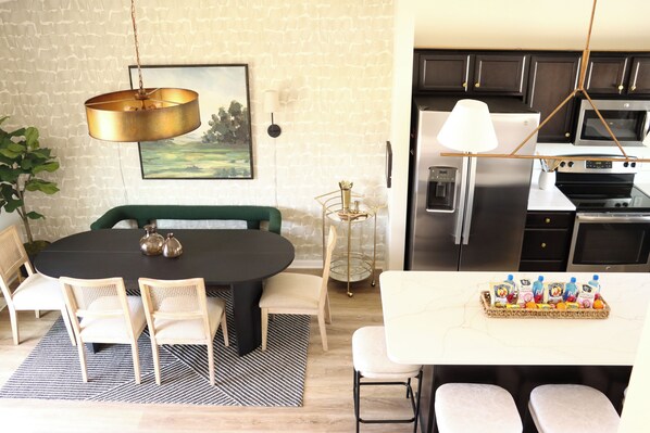 A modern kitchen with dark cabinets, stainless steel appliances, and a white countertop.