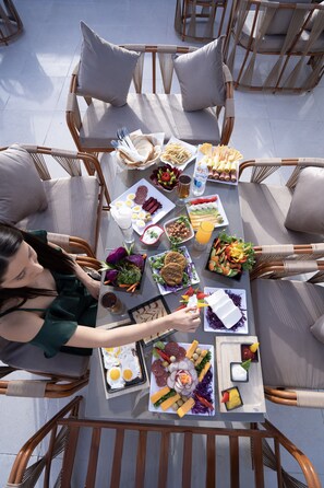 A dining table set with various food items and a person seated at the table. - king of pharaohs (Giza)