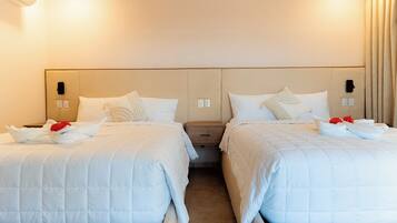 Ein Hotelzimmer mit zwei Betten, jeweils mit weißer Bettwäsche und Kissen, einem Nachttisch und einem an der Wand befestigten Telefon.