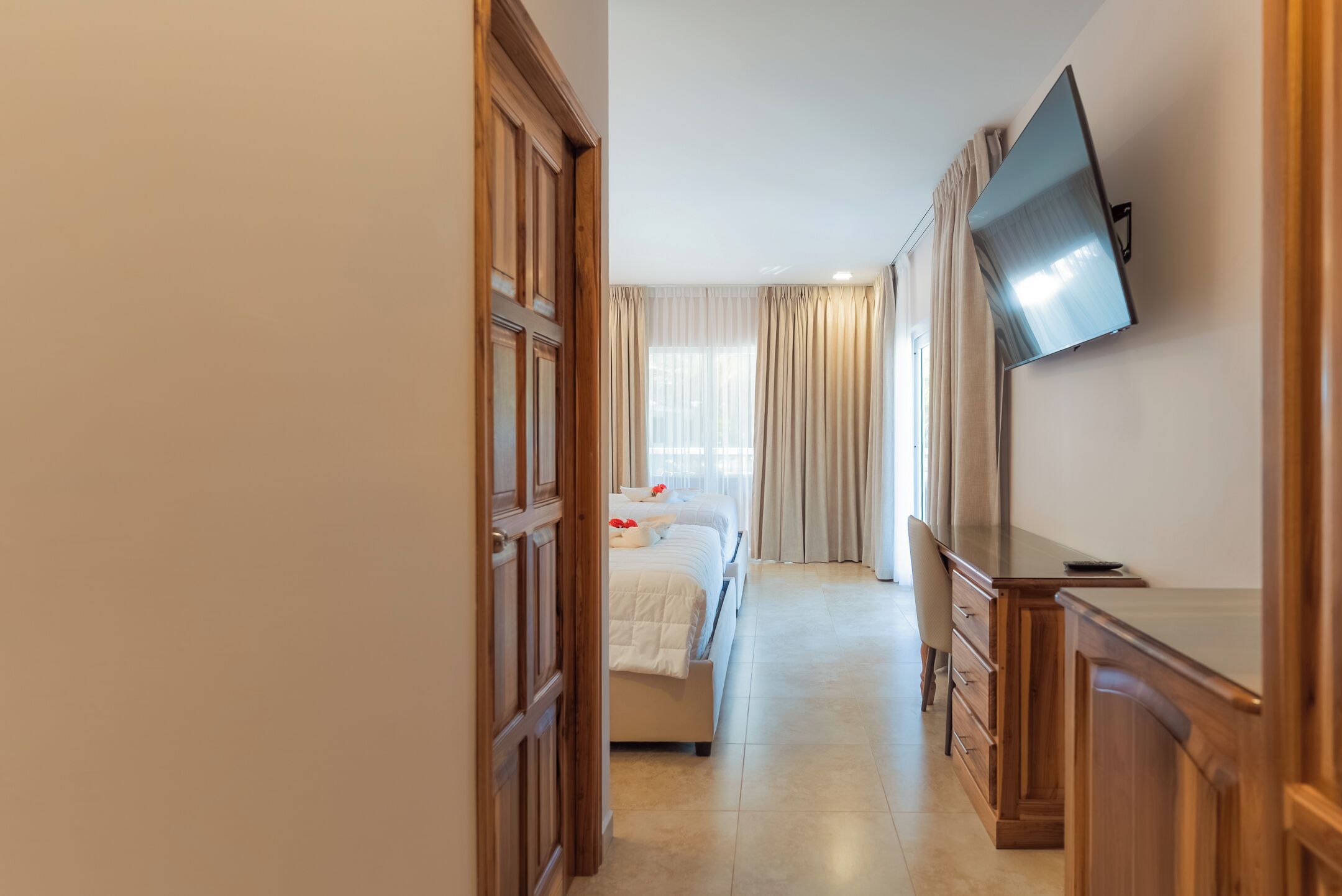 Habitación de hotel con una cama, un televisor en la pared y un aparador de madera.