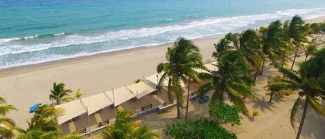 Na praia, areia branca, espreguiçadeiras, toalhas de praia