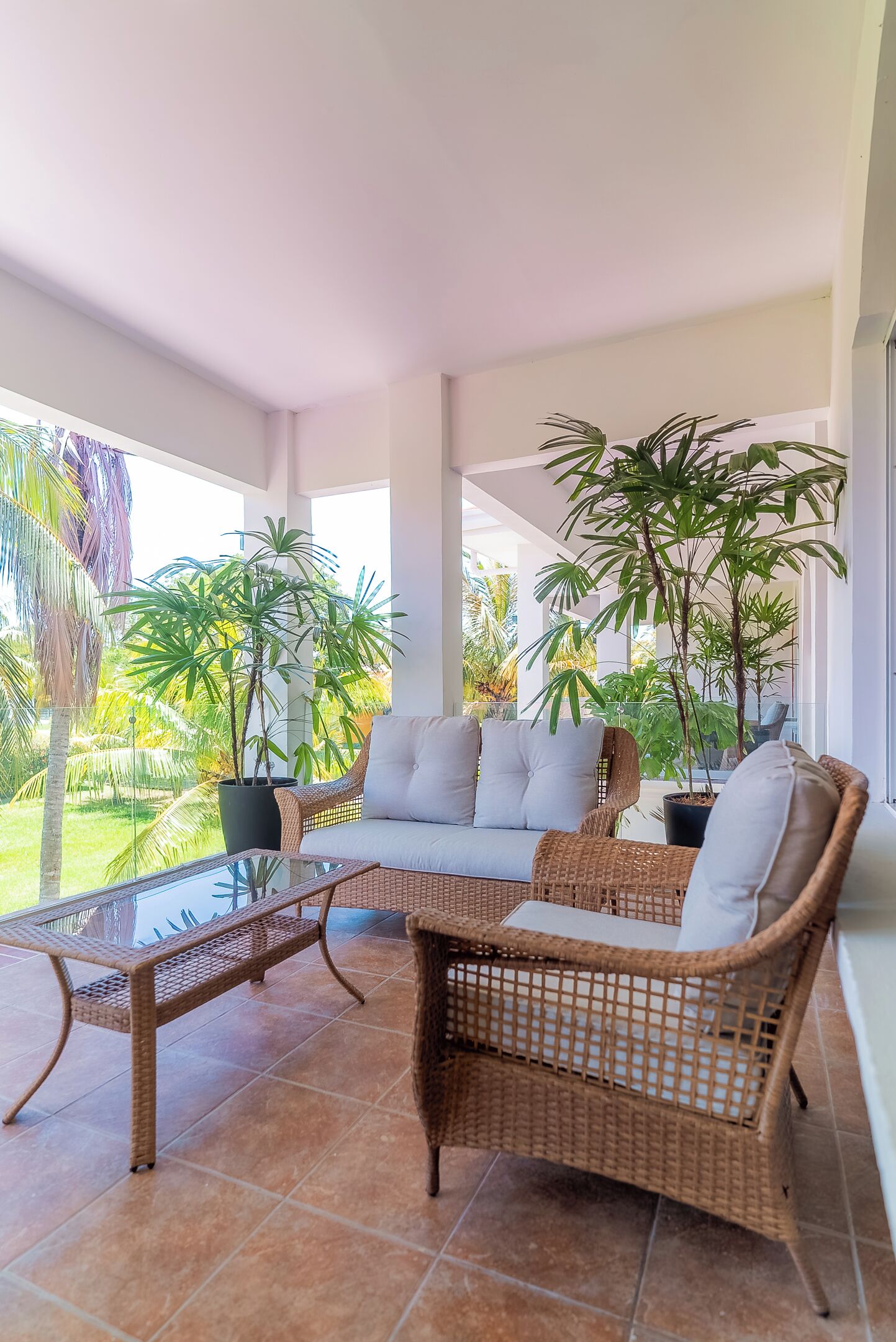 A covered outdoor seating area with wicker furniture and potted plants.