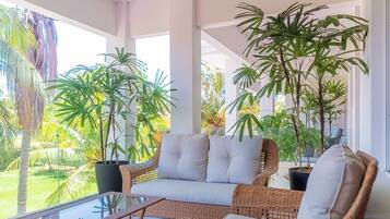 A covered outdoor seating area with wicker furniture and potted plants.