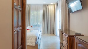 Habitación de hotel con cama, escritorio, televisión y baño con espejo.