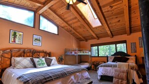 A cozy cabin-style bedroom with a large bed, two smaller beds, a bench, and a bunk bed. - Cozy 3-bedroom cabin in superb Arnold with WiFi and a Spa (Arnold)