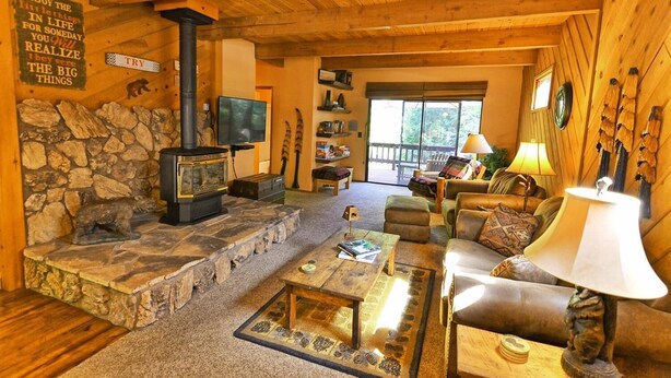 A cozy cabin interior with a stone fireplace, wooden furniture, and a television. - Cozy 3-bedroom cabin in superb Arnold with WiFi and a Spa (Arnold)