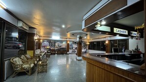Un hall de hotel con una recepción, zona de estar y vistas a la calle.