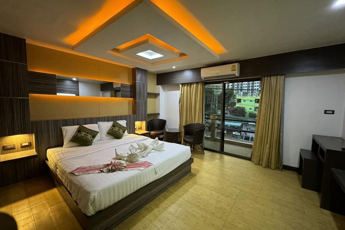 A modern hotel room with a large bed, a desk, and a view of the city.