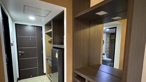 Un pasillo con una puerta de madera oscura, un refrigerador y un banco.