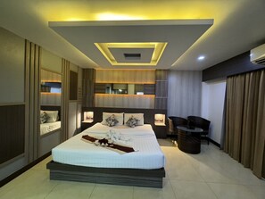 Une chambre d’hôtel moderne dotée d’un grand lit, de tables de chevet, d’un coin salon et d’un luminaire au plafond.