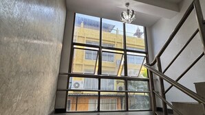 Una escalera con barandillas metálicas que lleva a un rellano con un ventanal grande.