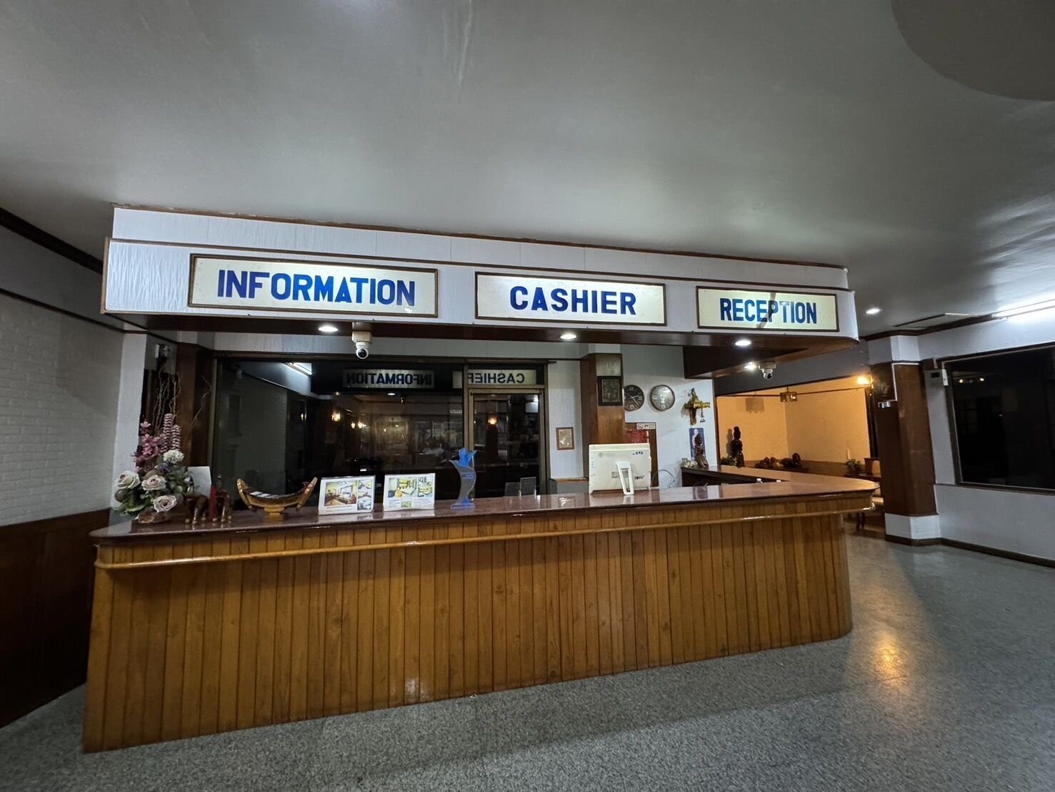 A reception desk with signs for 'Information', 'Cashier', and 'Reception'.