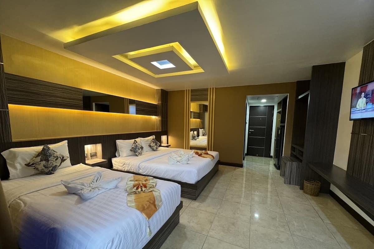 A hotel room with two beds, a TV, and a ceiling with recessed lighting.