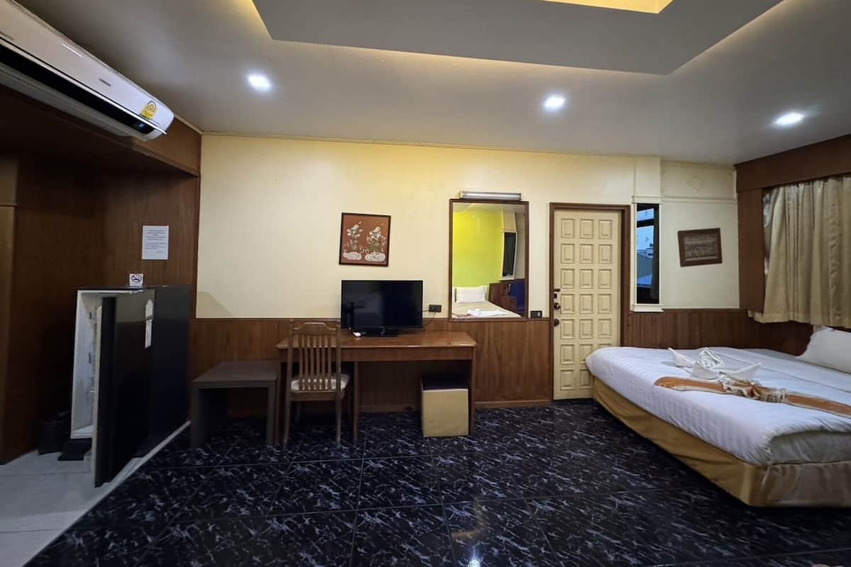 A hotel room with a bed, desk, chair, and a television.