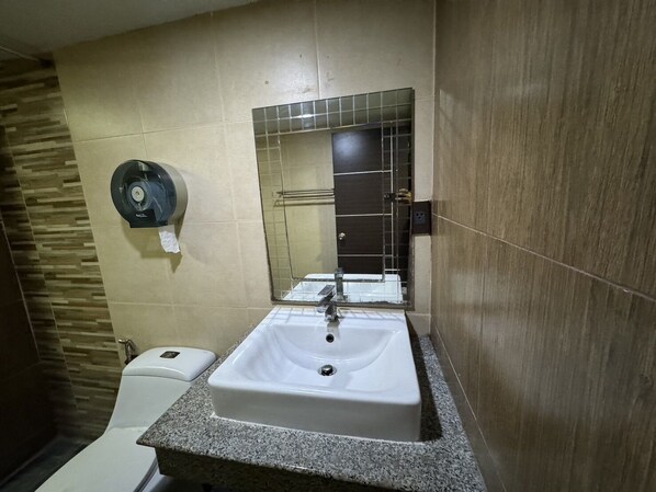 Une salle de bain avec un lavabo blanc, un miroir et un distributeur de serviettes en papier.
