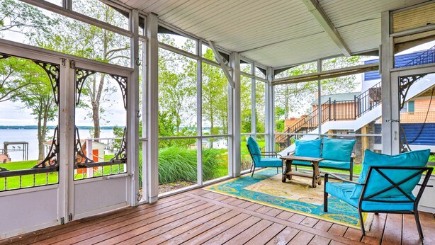 A covered outdoor area with wooden flooring, blue chairs, and a view of a lake. - WATERFRONT!!! The River's Roost on The Patuxent River (Saint Leonard)