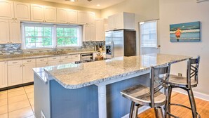 A modern kitchen with white cabinetry, a large island with bar stools, and a stainless steel refrigerator. - WATERFRONT!!! The River's Roost on The Patuxent River (Saint Leonard)