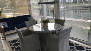 A sunlit room with a round table, wicker chairs, a blue sofa, and large windows with blinds. - Beach lovers paradise!  (Longboat Key)