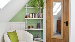 Una stanza con una sedia bianca, una porta in legno e una libreria con libri e oggetti decorativi.