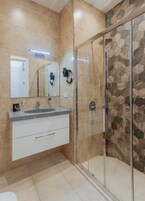 Un baño moderno con ducha de vidrio, un espejo grande y un lavamanos.