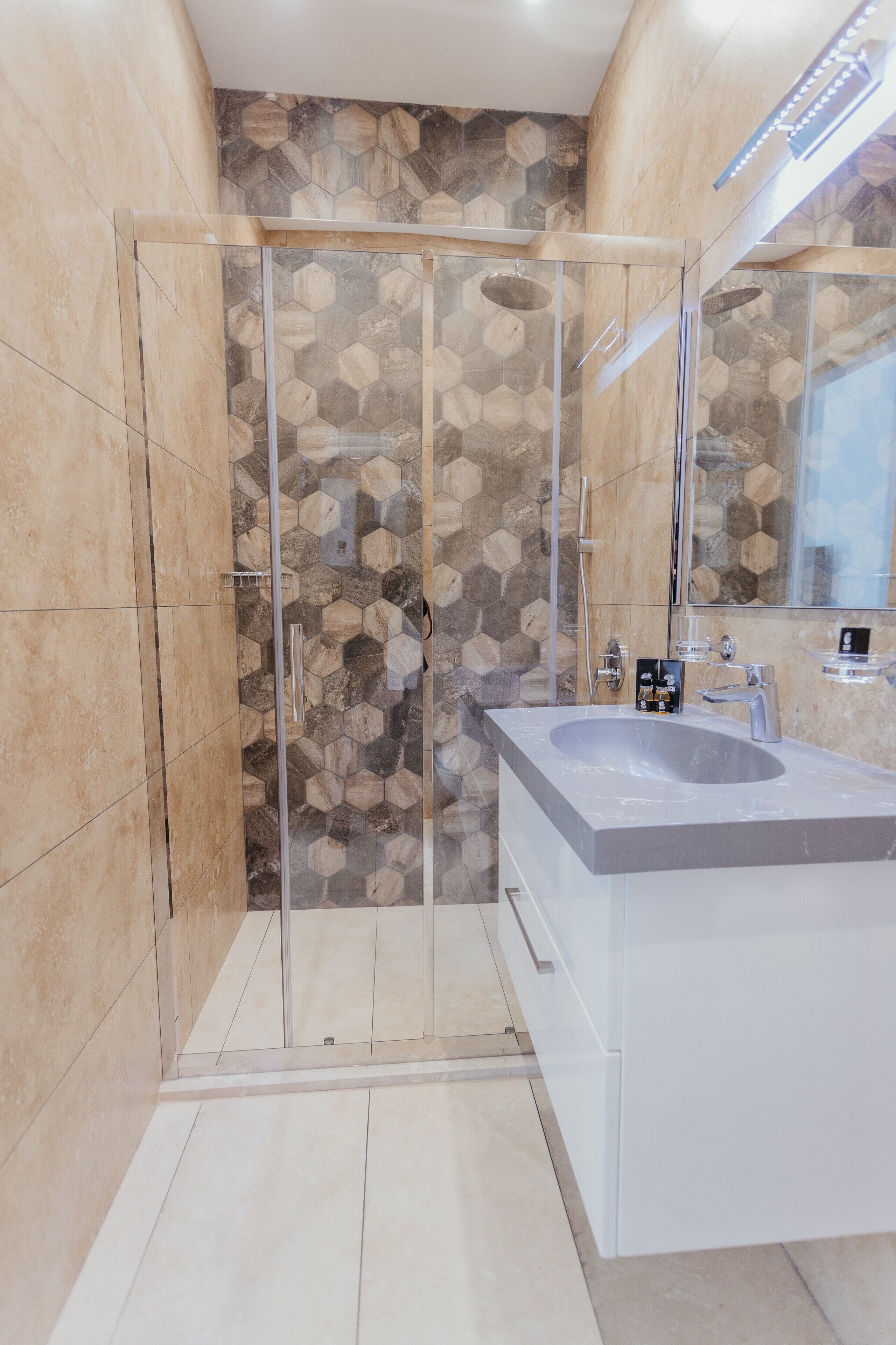 Un bagno moderno con doccia a vetro, un lavandino ampio e una parete decorata con motivi in pietra.