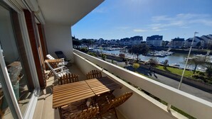 A balcony with a wooden table and chairs, overlooking a marina with boats and buildings. - Appartement Très Agréable Avec vue Dégagée Proche de la Plage et des Commerces (La Baule-Escoublac)
