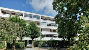 A multi-story building with a modern design, surrounded by trees and a gravel path. - Appartement Très Agréable Avec vue Dégagée Proche de la Plage et des Commerces (La Baule-Escoublac)