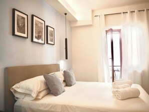 A bedroom with a bed, pillows, a bedside table, and a window with curtains.