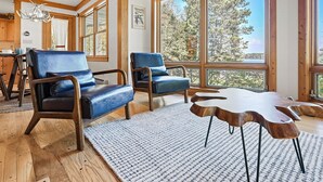 A spacious room with large windows, wooden flooring, and a modern chair and table arrangement. - Buckatabon Lakeside Retreat. Direct access to snowmobile trails! (Conover)