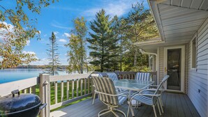 A deck with a table and chairs, overlooking a lake and surrounded by trees. - Buckatabon Lakeside Retreat. Direct access to snowmobile trails! (Conover)
