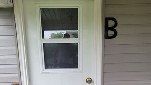 A white door with a small window, a wooden bench, and a letter 'B' on the wall.