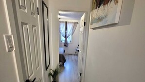 A hallway with white doors, a wooden floor, and a painting on the wall.