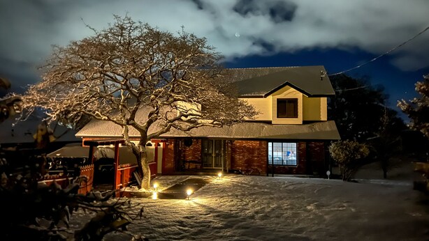 A house with a sloped roof, a visible chimney, and a snow-covered ground.