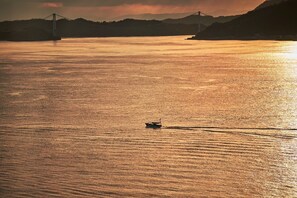 A boat on a calm body of water with a bridge in the background.