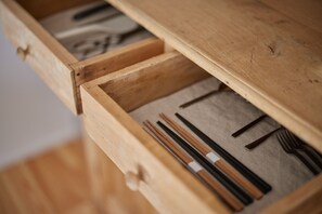 A wooden drawer with chopsticks, a fork, and a knife.