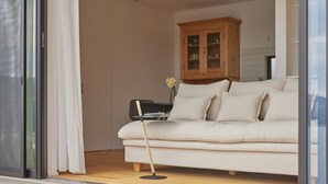 A modern living room with a sofa, a wooden cabinet, and a dining table.