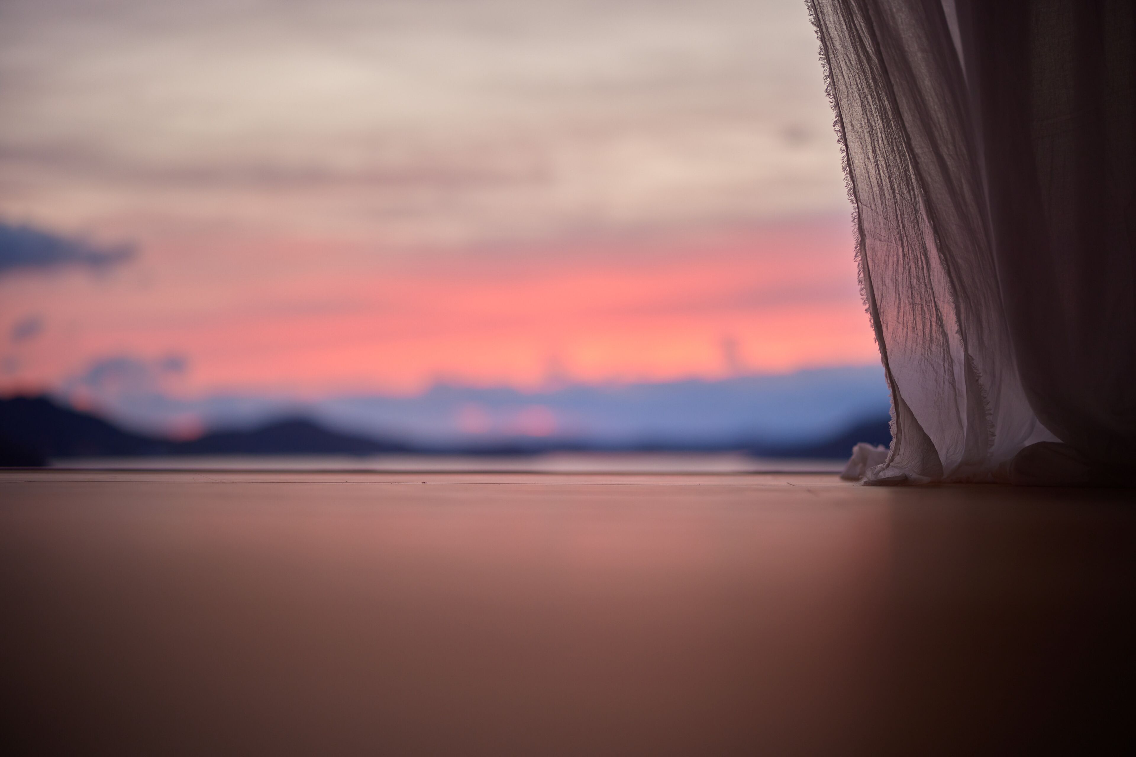 Una habitación con vista a un atardecer sobre el agua.