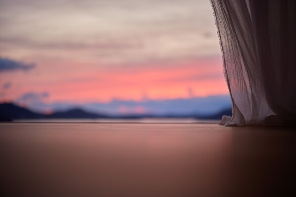 A room with a view of a sunset over a body of water.