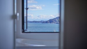 A view through a window of a coastal landscape with mountains and a bridge.