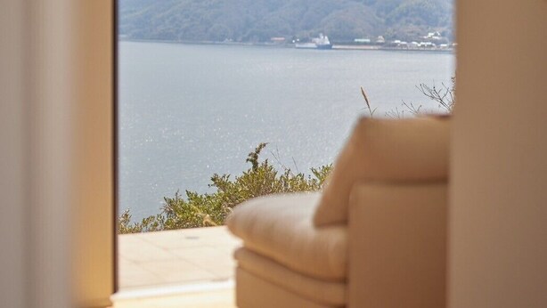 A room with a large sliding glass door leading to a scenic view of a lake and mountains.