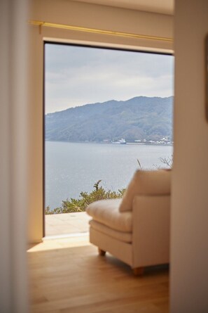 Una habitación con un amplio ventanal corredera que da a una vista panorámica de un lago y montañas.