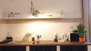 A modern kitchen with a wooden countertop, a sink, and various appliances including a coffee maker and a kettle. - Bright and confortable apartment in the center of the liveliest part of the city (Napoli)