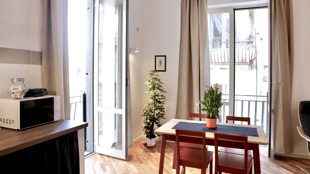 A modern kitchen with a microwave, wooden cabinets, and a sliding glass door leading to a balcony. - Bright and confortable apartment in the center of the liveliest part of the city (Napoli)