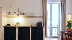 A kitchen with a wooden countertop, a microwave, and a sink. There is a window with curtains and a door leading outside. - Bright and confortable apartment in the center of the liveliest part of the city (Napoli)