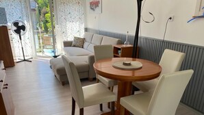 A modern living room with a round wooden table, white leather chairs, a beige sofa, and a fan. - Müllers Ferienhaus Harmonie (Dombovar)
