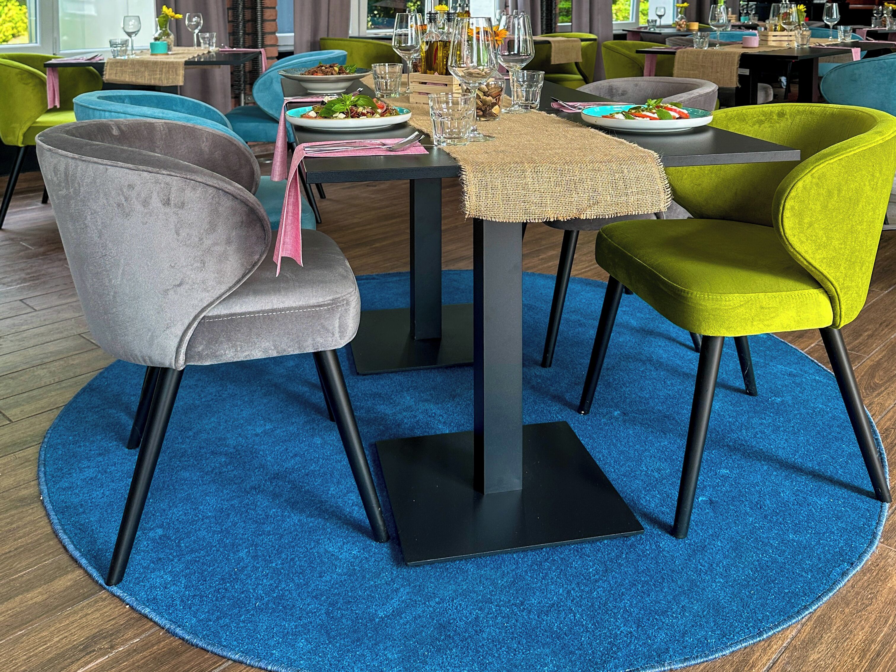Un comedor con una mesa redonda, sillas y una alfombra azul.
