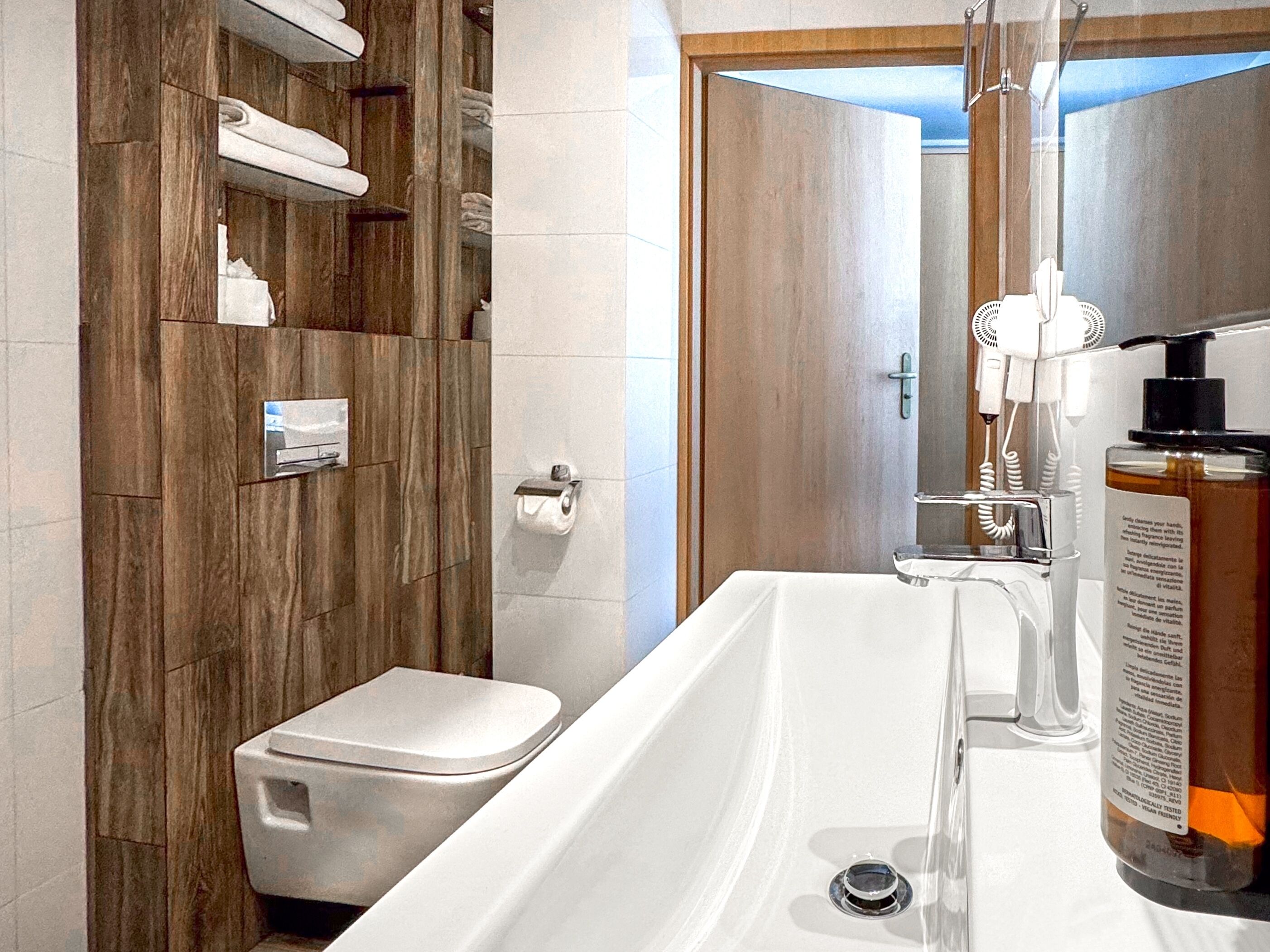 A modern bathroom with a wooden vanity, a toilet, and a large bathtub.