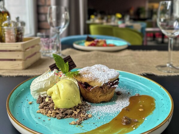 A dessert with ice cream, a muffin, and a sauce on a turquoise plate. - Hotel Malinowski Leśny (Gliwice)
