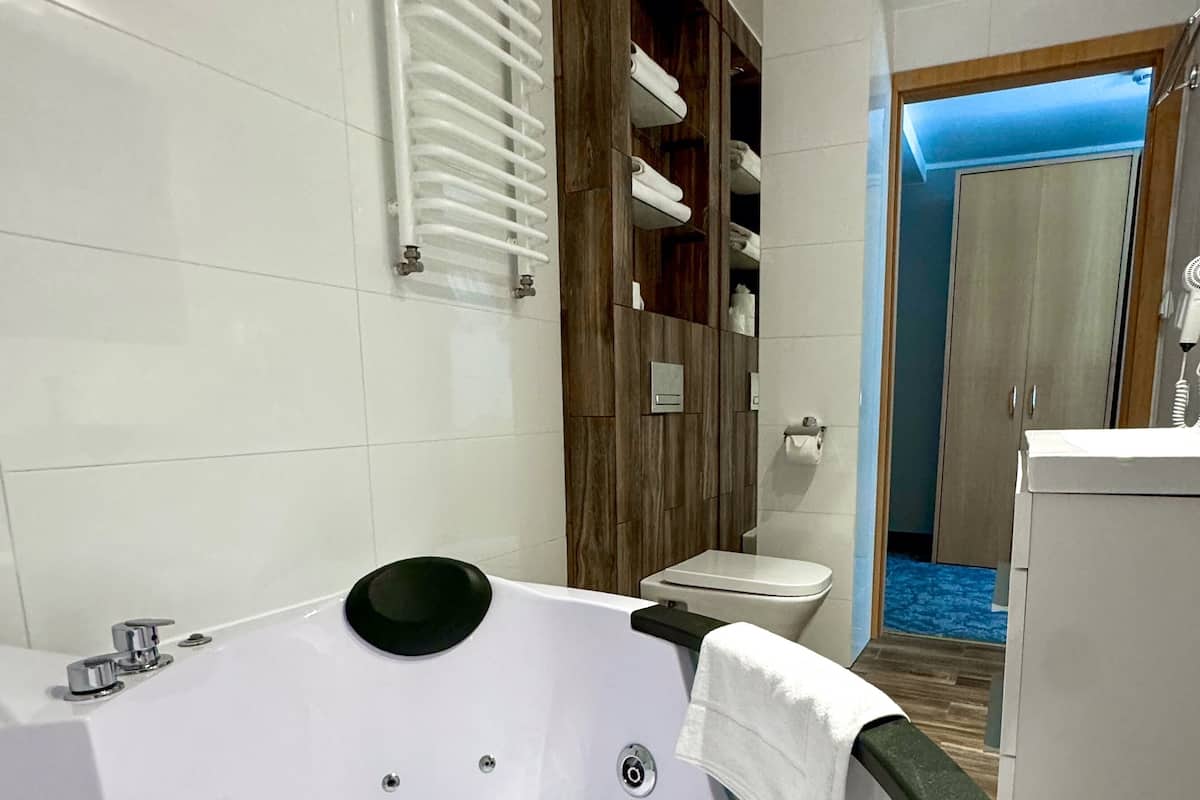 A modern bathroom with a large bathtub, a wooden vanity, and a shower area.